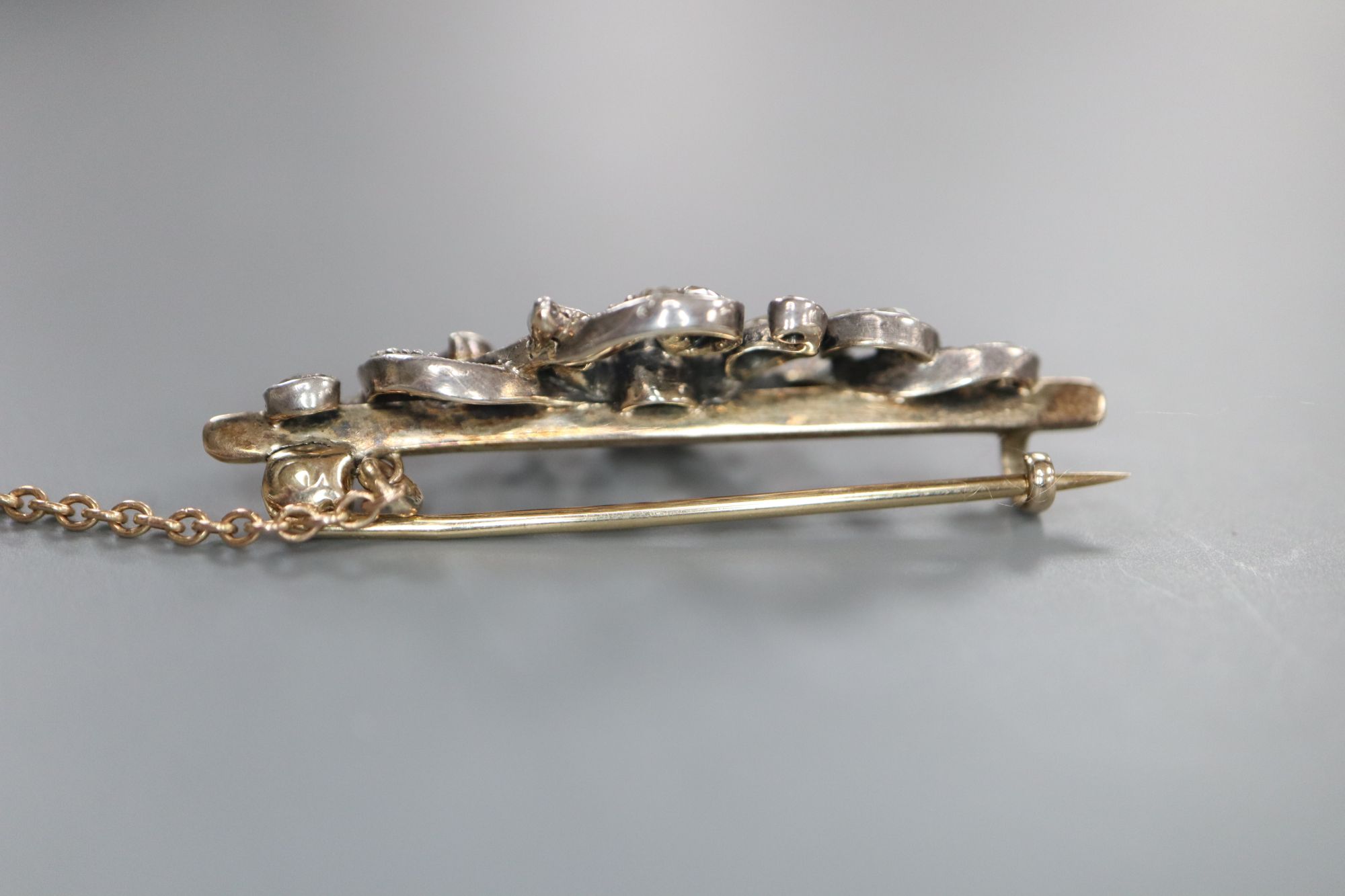 A Victorian yellow and white metal, round and rose cut diamond set scrolling bar brooch, 36mm, gross 3.8 grams.